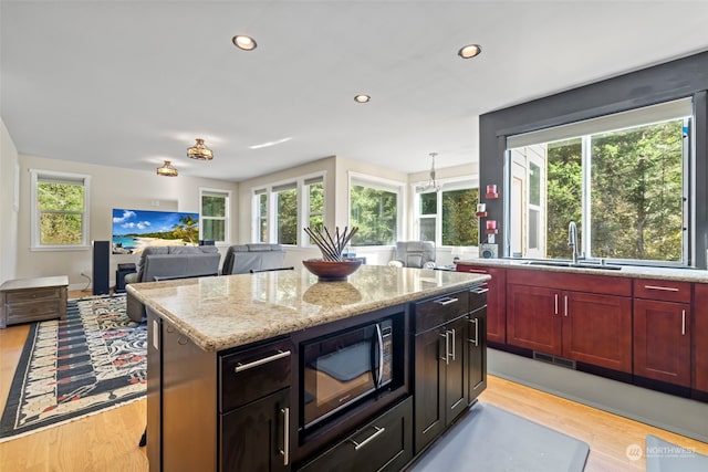 kitchen with recessed lighting, light wood-style flooring, a sink, light stone countertops, and black microwave