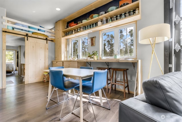 dining area featuring a barn door and dark hardwood / wood-style floors