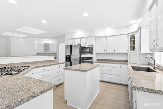 kitchen featuring stainless steel appliances, white cabinets, light hardwood / wood-style flooring, and a center island