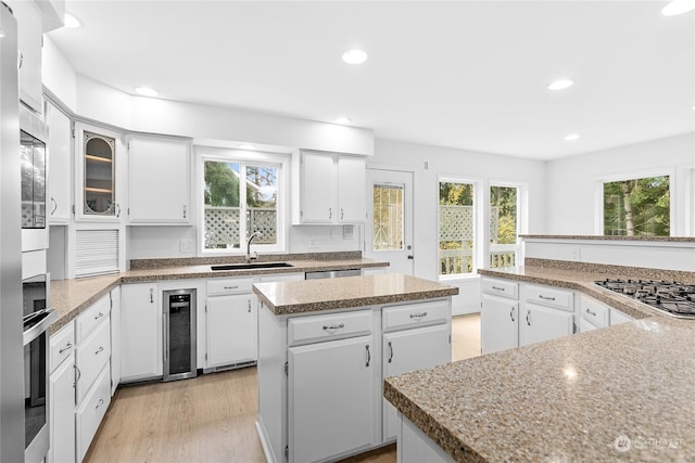 kitchen with wine cooler, sink, plenty of natural light, a center island, and white cabinets