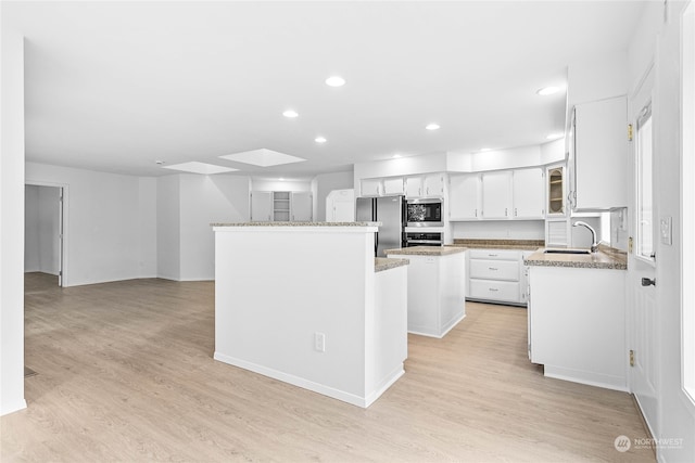 kitchen featuring stainless steel appliances, sink, a center island, and light hardwood / wood-style flooring