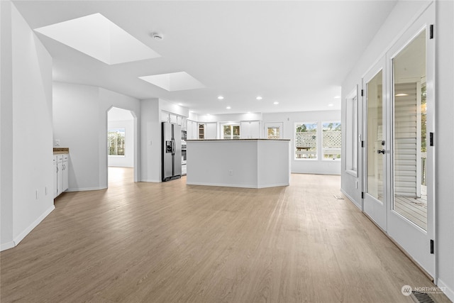 unfurnished living room featuring a skylight and light hardwood / wood-style flooring