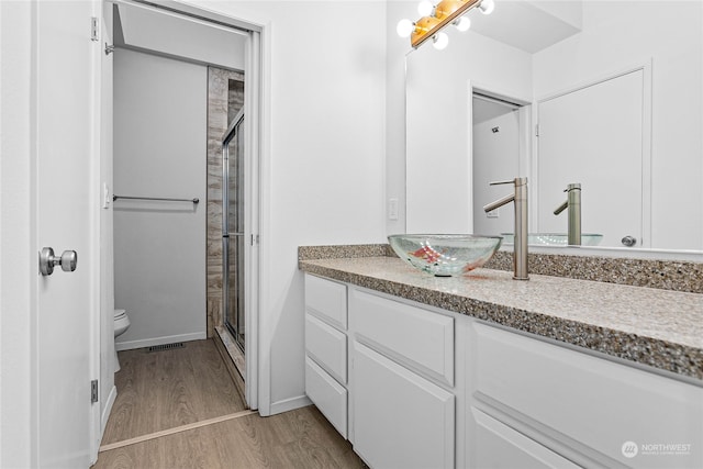 bathroom with a shower with door, wood-type flooring, toilet, and vanity