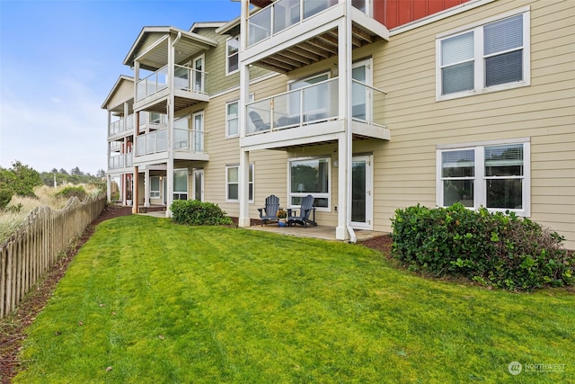 back of house featuring a lawn, a balcony, and a patio