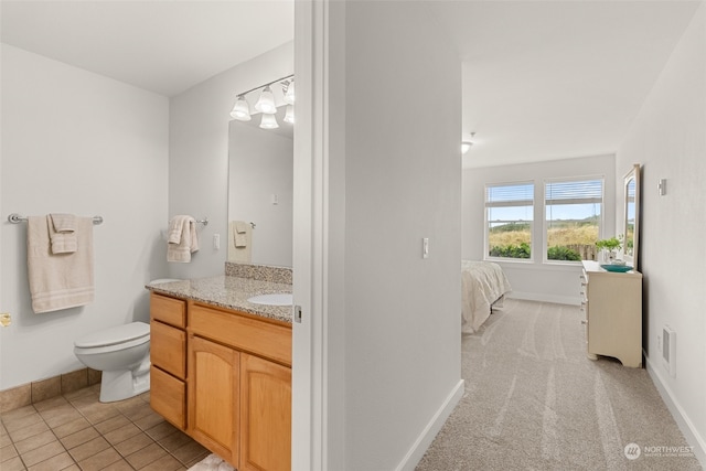 bathroom with toilet, vanity, and tile patterned flooring