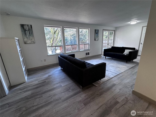 living area featuring visible vents, a textured ceiling, baseboards, and wood finished floors