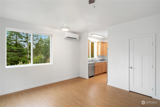 unfurnished living room featuring sink, ceiling fan, a wall mounted AC, and light hardwood / wood-style flooring