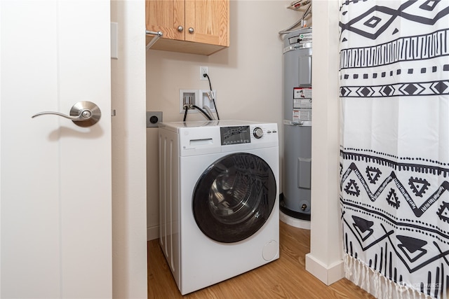 clothes washing area featuring washer / dryer, electric water heater, cabinets, and light wood-type flooring