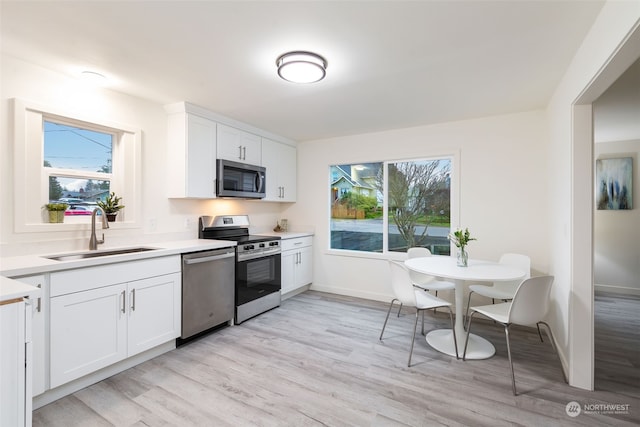 kitchen with sink, appliances with stainless steel finishes, a healthy amount of sunlight, and white cabinetry