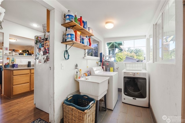 clothes washing area featuring washing machine and dryer, sink, and light wood-type flooring