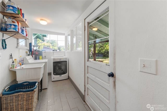 clothes washing area featuring sink, washing machine and clothes dryer, and a wealth of natural light