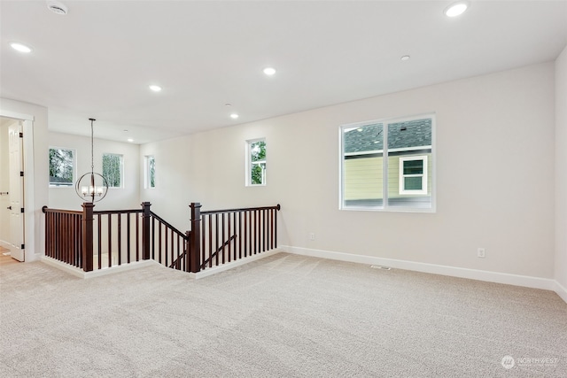 spare room with light carpet and an inviting chandelier