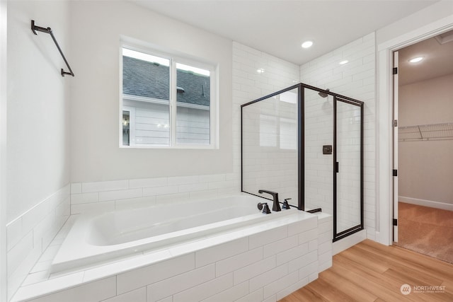 bathroom featuring plus walk in shower and wood-type flooring