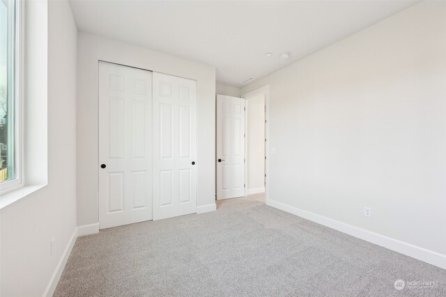 unfurnished bedroom featuring a closet and light colored carpet