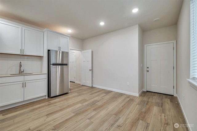 13307 Pines Ln E, Puyallup, WA 98374 - kitchen featuring freestanding refrigerator, a sink, light wood-type flooring, backsplash, and white cabinets