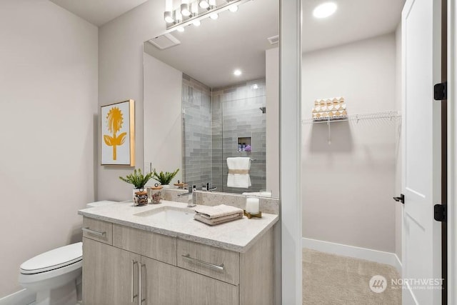 bathroom with vanity, tiled shower, and toilet