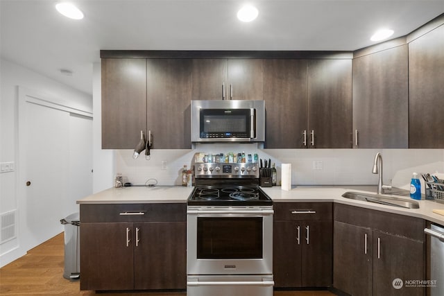 kitchen featuring sink, appliances with stainless steel finishes, dark brown cabinets, and light hardwood / wood-style floors