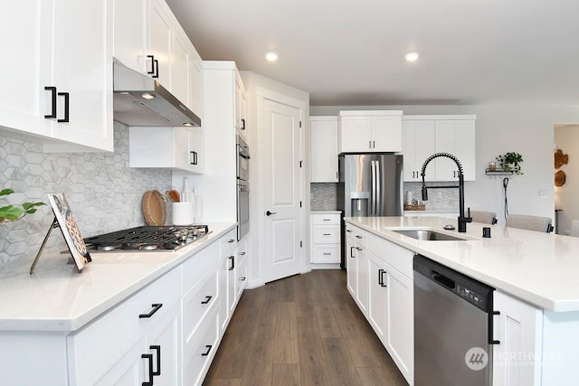 kitchen with dark hardwood / wood-style flooring, appliances with stainless steel finishes, extractor fan, an island with sink, and sink