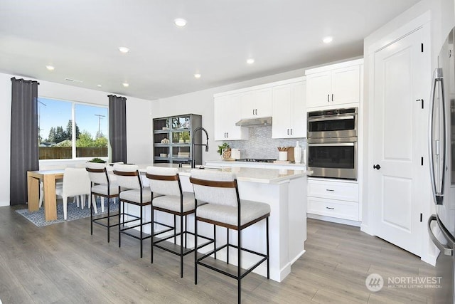 1121 SE 33rd St, Battle Ground, WA 98604 - kitchen with an island with sink, a sink, stainless steel appliances, under cabinet range hood, and tasteful backsplash
