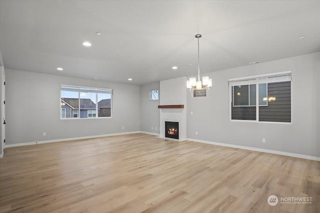 unfurnished living room with a chandelier and light hardwood / wood-style flooring