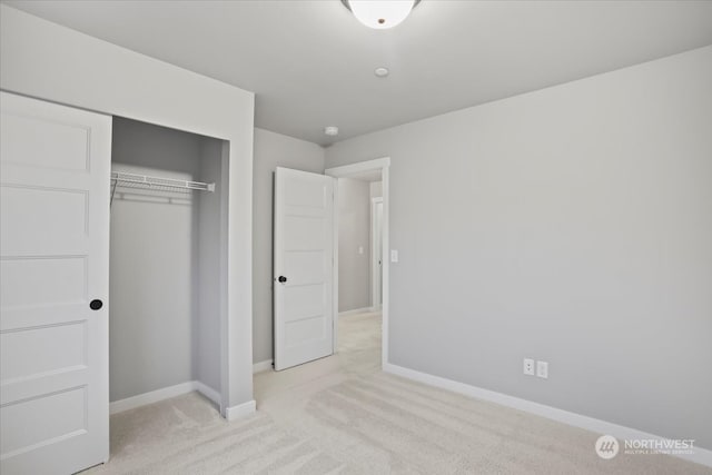 unfurnished bedroom featuring light colored carpet and a closet