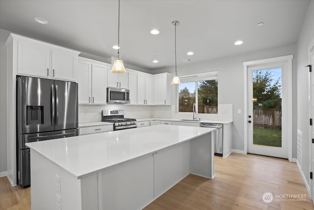 kitchen with white cabinets, light wood-type flooring, appliances with stainless steel finishes, and a center island