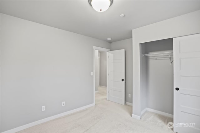 unfurnished bedroom featuring light carpet and a closet