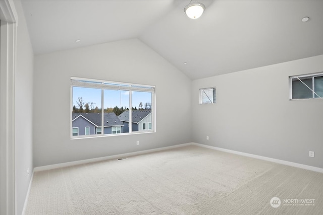 carpeted empty room with a healthy amount of sunlight and vaulted ceiling