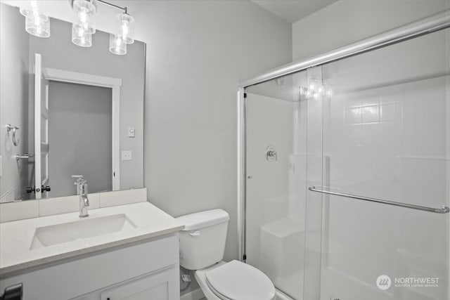 bathroom featuring toilet, vanity, and a shower with shower door