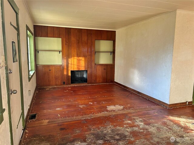 unfurnished living room featuring crown molding and dark wood-type flooring