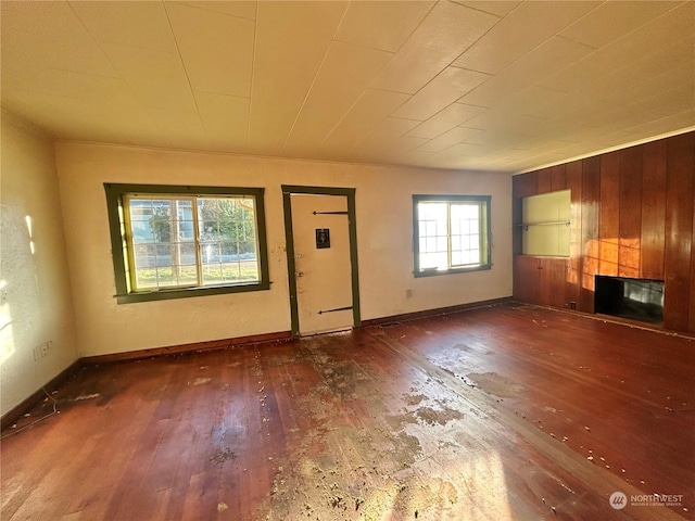 unfurnished living room with wooden walls and dark hardwood / wood-style floors