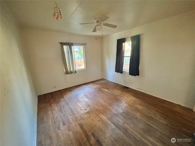 empty room featuring wood-type flooring, a healthy amount of sunlight, and ceiling fan