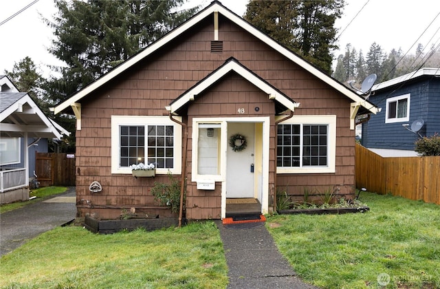 bungalow-style home featuring entry steps, a front yard, and fence