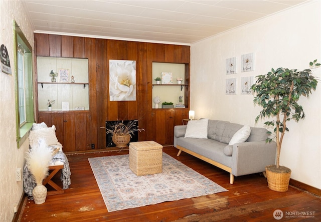 living room featuring ornamental molding, dark wood-type flooring, and wood walls