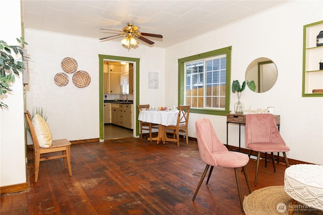 sitting room with dark wood-style floors, crown molding, a ceiling fan, and baseboards