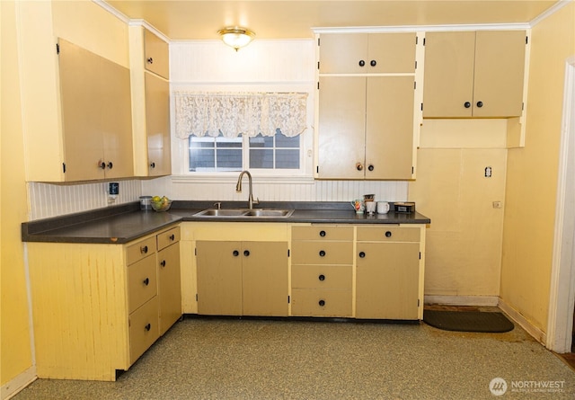 kitchen featuring dark countertops, baseboards, and a sink