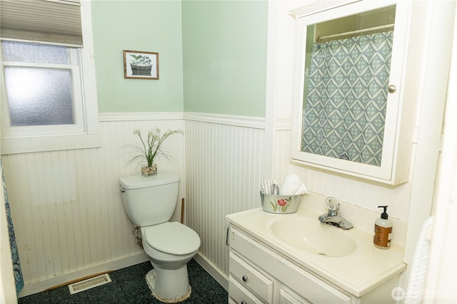 bathroom with a wainscoted wall, visible vents, toilet, and vanity