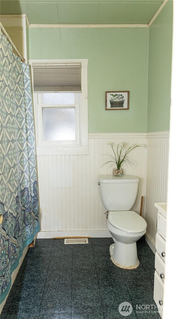 full bath with a wainscoted wall, visible vents, toilet, and crown molding