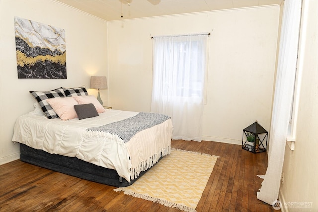 bedroom with dark wood-style floors, baseboards, and crown molding