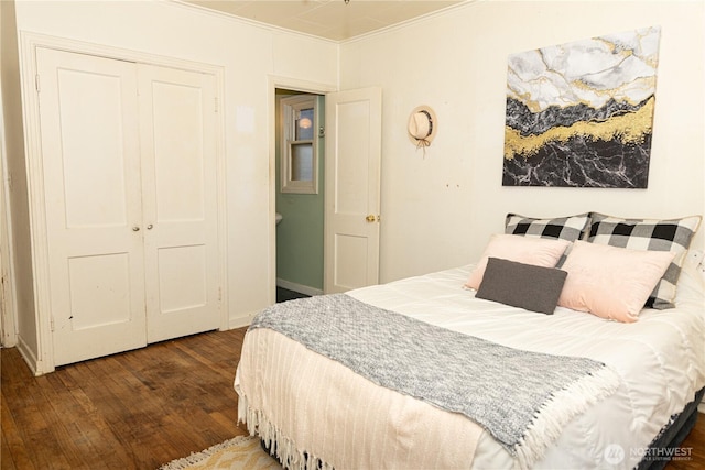 bedroom featuring dark wood-type flooring, ornamental molding, and a closet