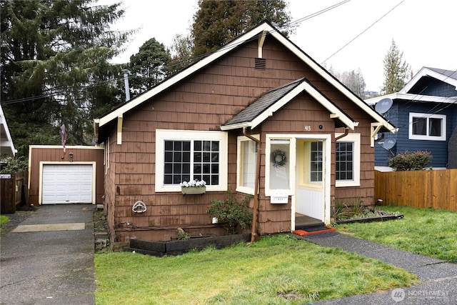 bungalow-style home with an attached garage, aphalt driveway, a front yard, and fence