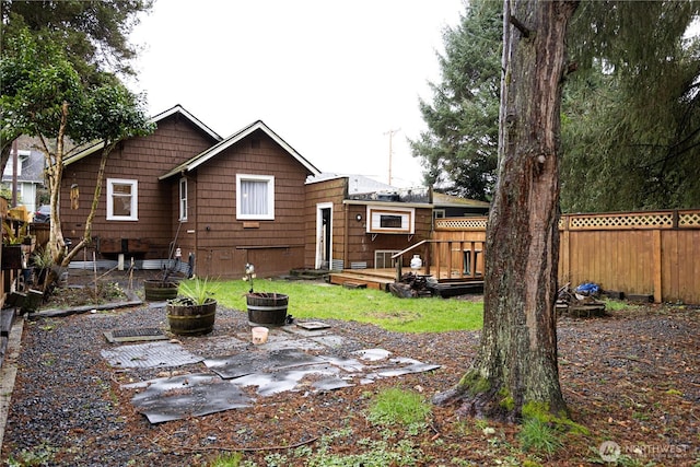 back of property with fence and a wooden deck