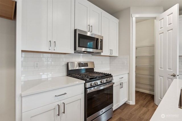 kitchen with white cabinetry, stainless steel appliances, and hardwood / wood-style flooring