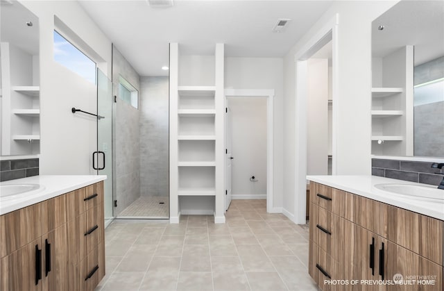 bathroom with vanity, a shower with shower door, plenty of natural light, and tile patterned floors