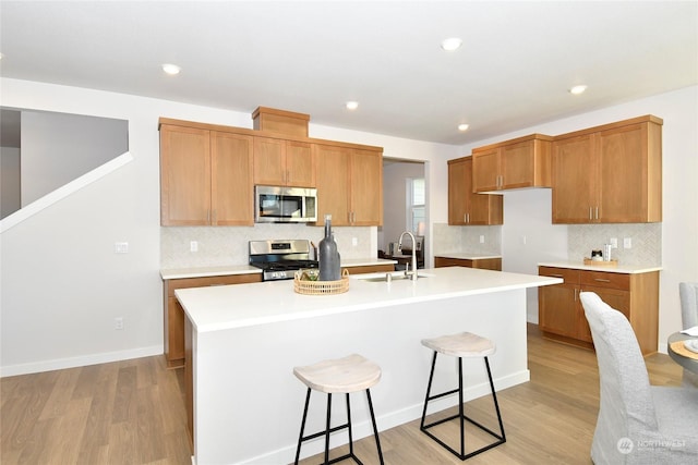 kitchen featuring sink, stainless steel appliances, a kitchen island with sink, and light hardwood / wood-style flooring