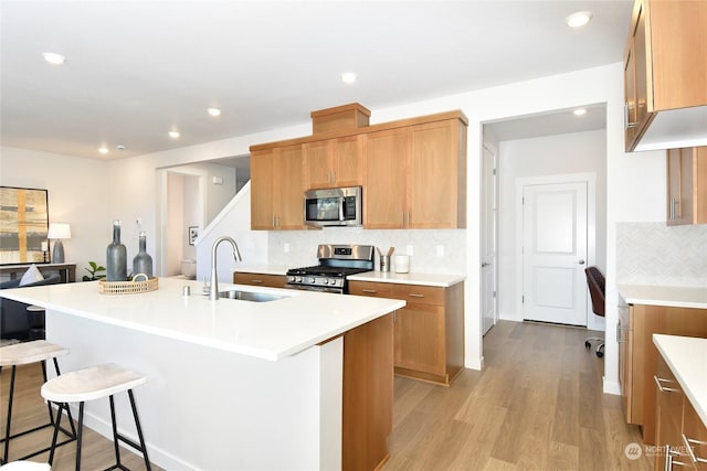 1112 SE 33rd St, Battle Ground, WA 98604 - kitchen featuring stainless steel appliances, a kitchen bar, decorative backsplash, light wood-style flooring, and recessed lighting