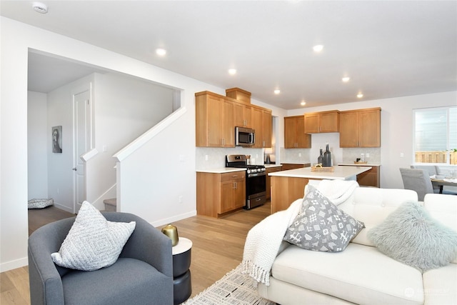 kitchen featuring tasteful backsplash, a center island, stainless steel appliances, and light hardwood / wood-style floors