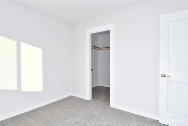 unfurnished bedroom featuring light colored carpet, a walk in closet, and a closet