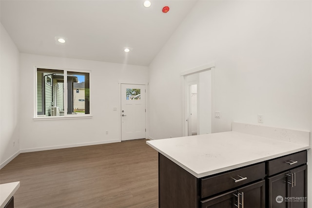 kitchen featuring dark brown cabinets, kitchen peninsula, high vaulted ceiling, and light hardwood / wood-style flooring