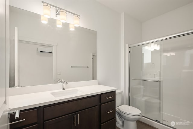 bathroom featuring an AC wall unit, vanity, an enclosed shower, and toilet